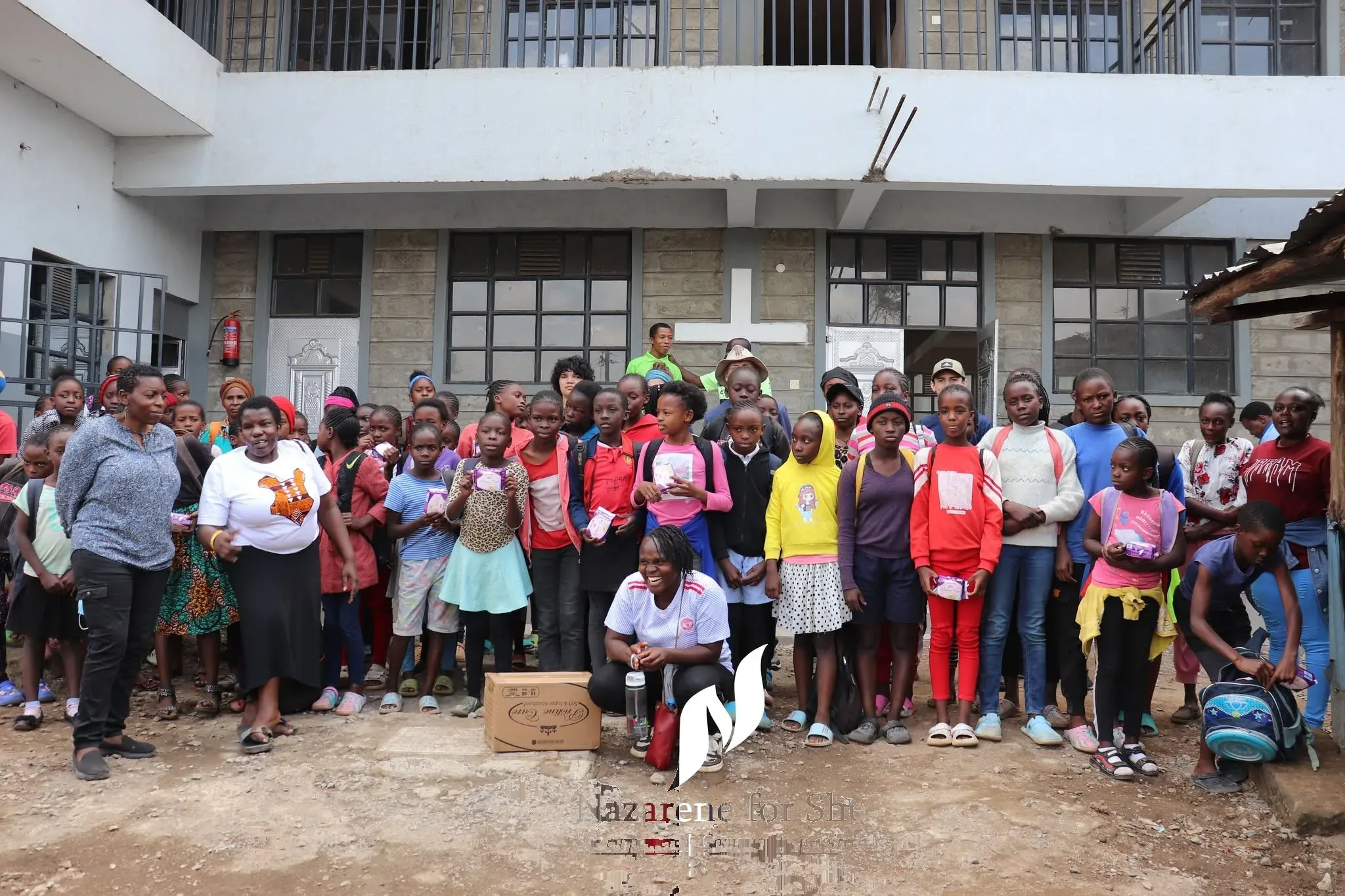 Girls supported by Nazarene for She gathered outside school with dignity kits — staying in education with confidence.